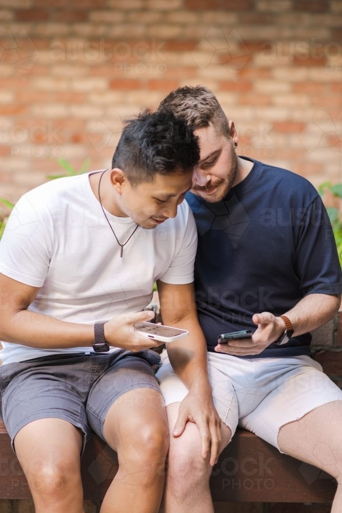 two men looking at the screens of their phone. - Australian Stock Image