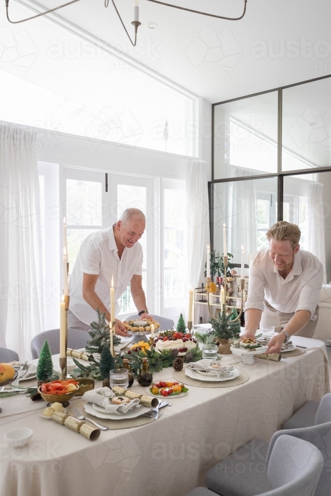 Two men setting up Christmas table together - Australian Stock Image