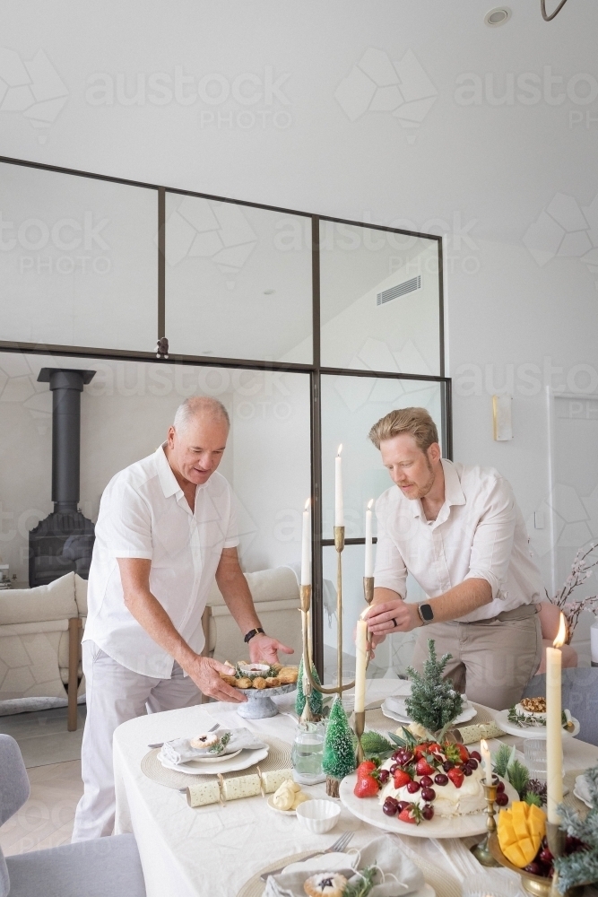 Two men setting up Christmas table together - Australian Stock Image