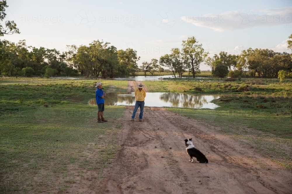 Two men talking at a flooded creek in the country - Australian Stock Image