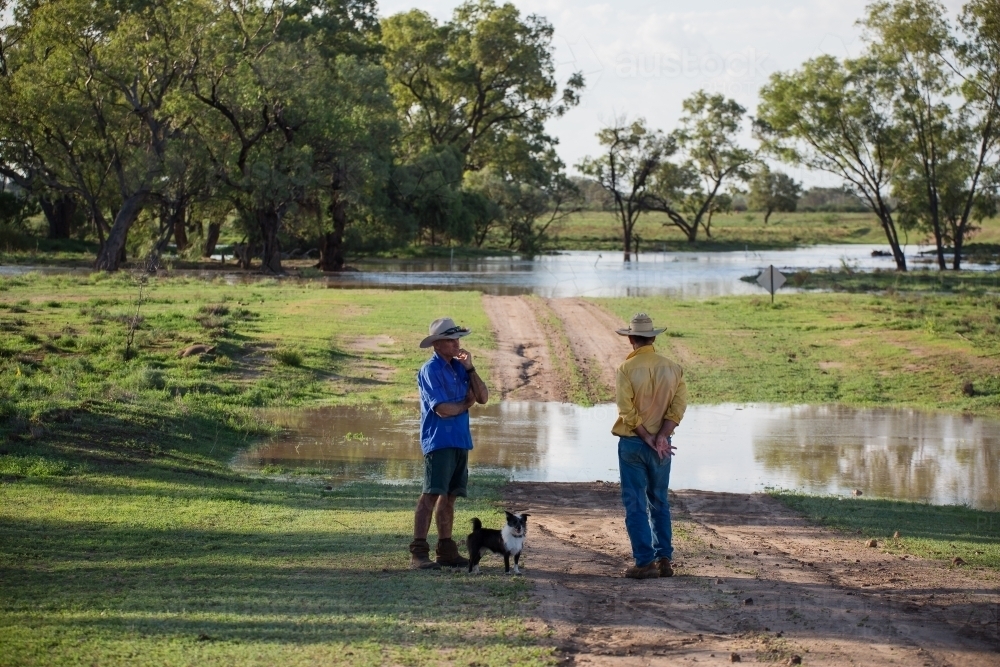 Two men talking near a flooded creek - Australian Stock Image