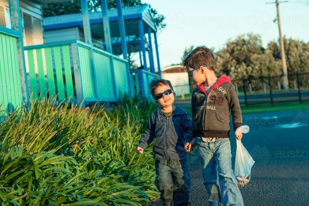 Two mixed race brothers holding hands and walking through a coastal NSW holiday park - Australian Stock Image