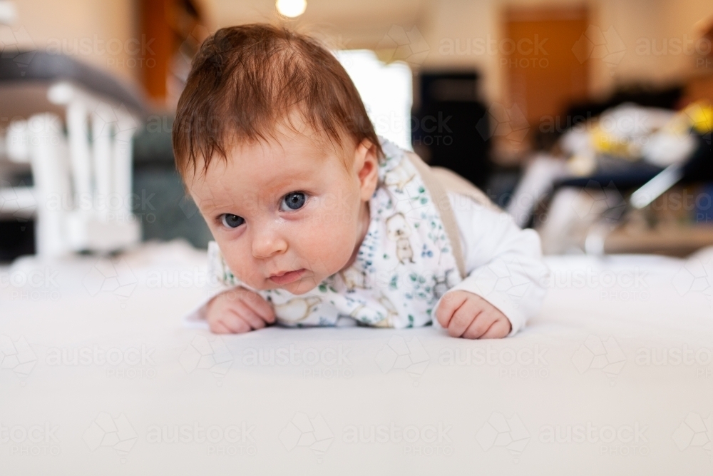 Two month old baby doing tummy time on white mat with copy space - Australian Stock Image
