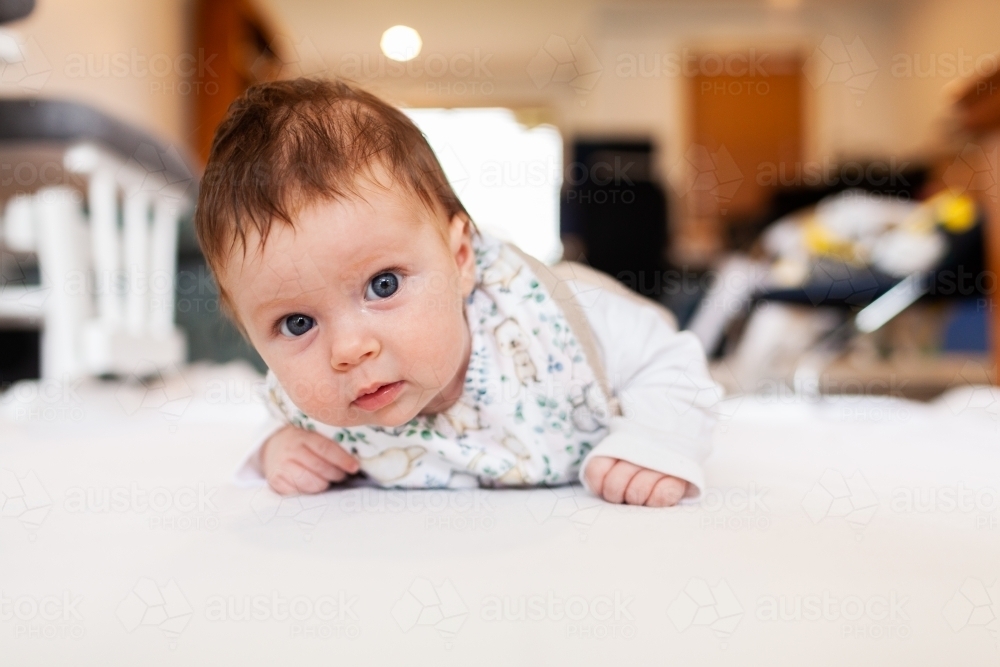 Two month old baby doing tummy time on white mat with copy space - Australian Stock Image