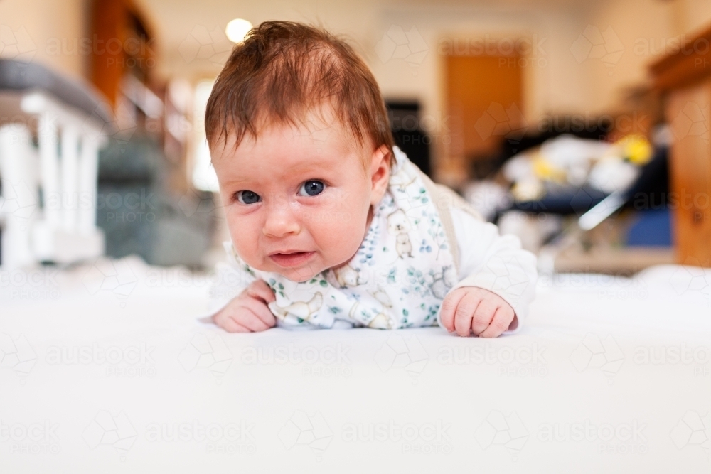 Two month old baby doing tummy time on white mat with copy space - Australian Stock Image