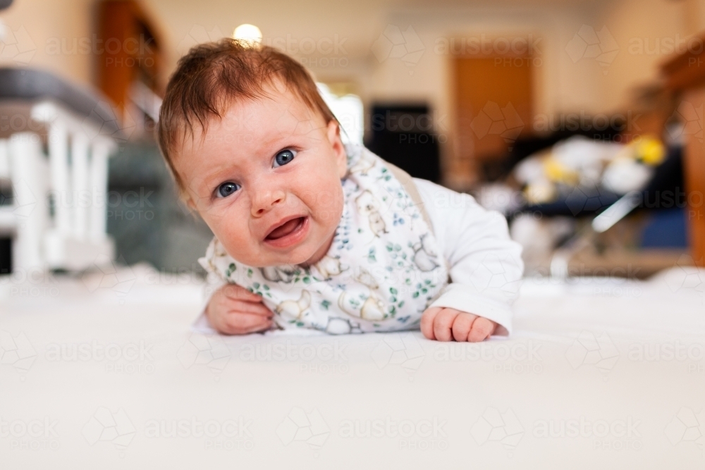 Two month old baby doing tummy time on white mat with copy space - Australian Stock Image