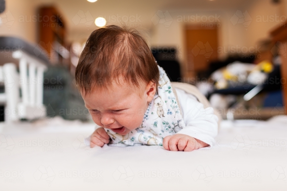 Two month old baby doing tummy time on white mat with copy space - Australian Stock Image