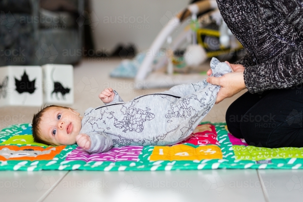 two month old happy baby on floor playing with parent - Australian Stock Image