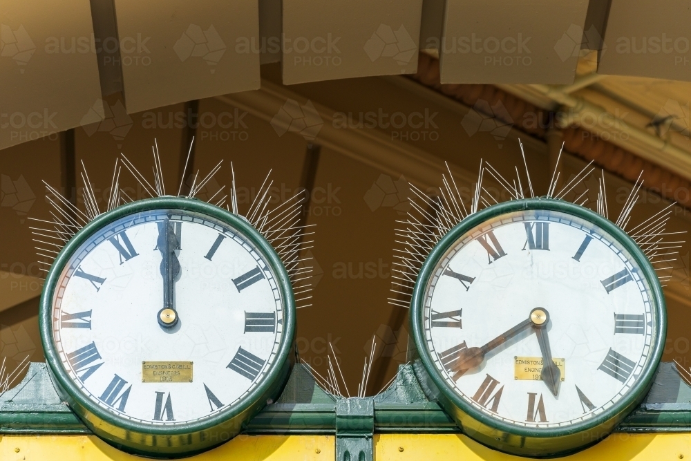 Two old fashioned railway clocks with bird spikes under a archway. - Australian Stock Image