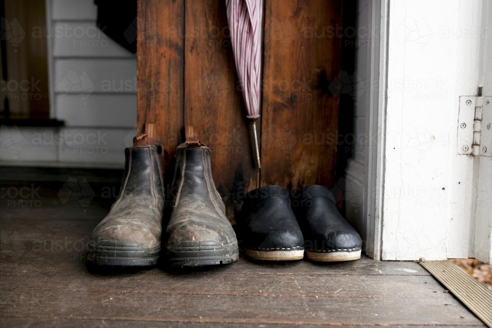 Two pairs of shoes lined up inside doorway of home - Australian Stock Image