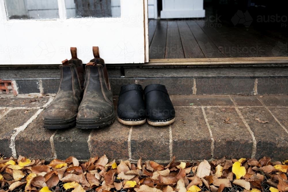 Two pairs of shoes lined up on step outside in autumn - Australian Stock Image