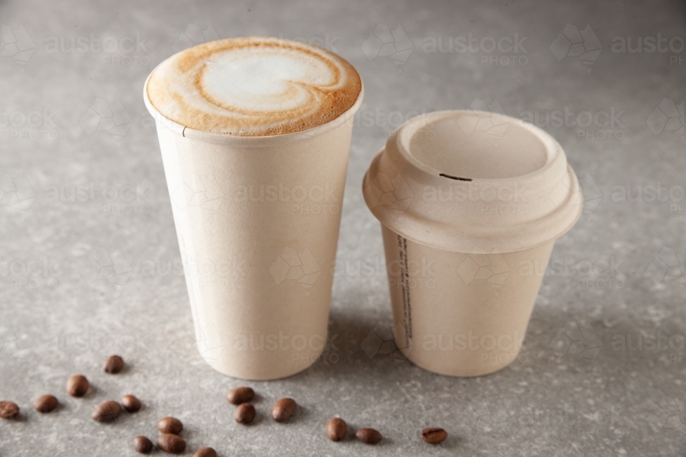 Image of Two paper coffee cup sizes on table full of warm beverage