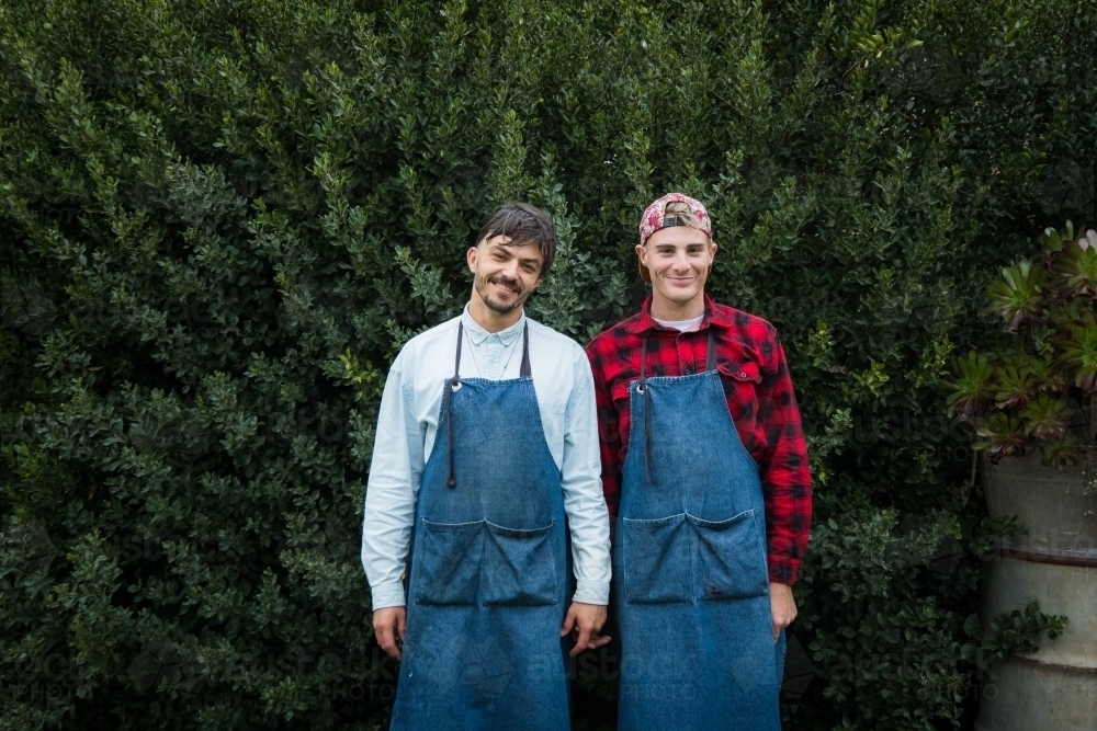Two partners at work in their aprons smiling. - Australian Stock Image