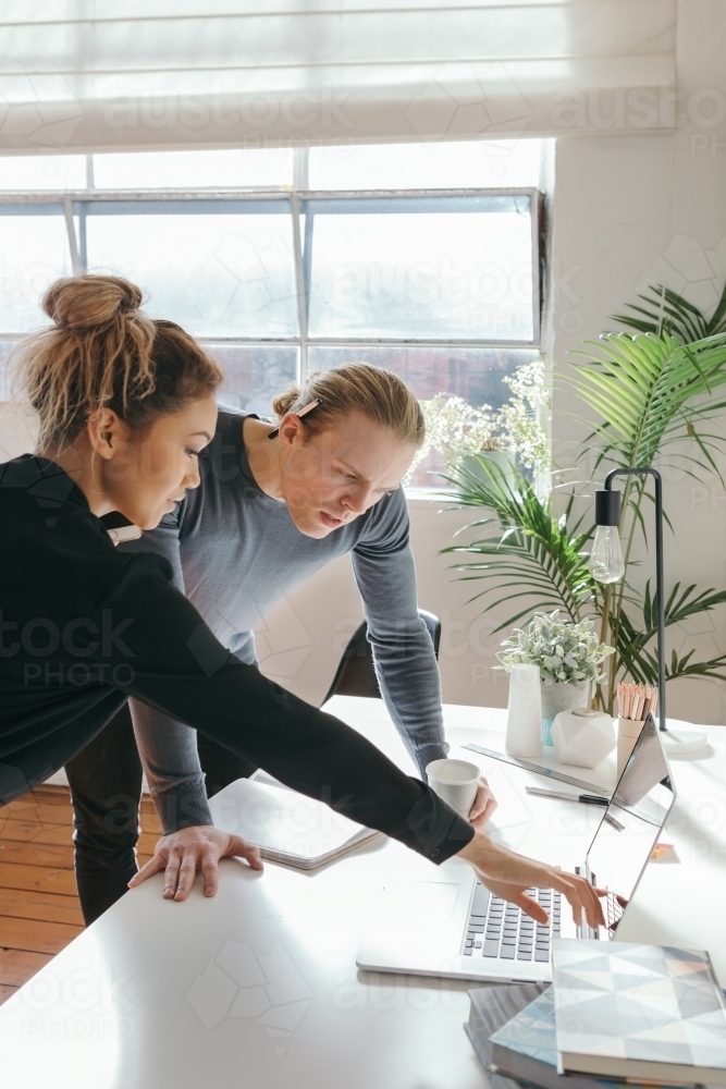 Two people discussing a problem with a laptop - Australian Stock Image