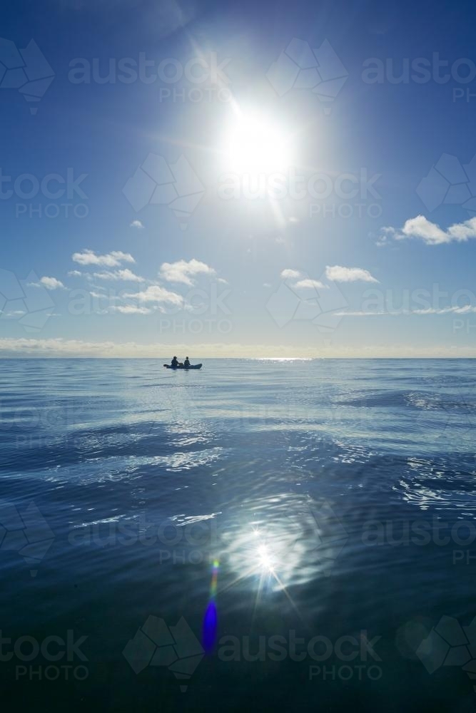 Two people paddle a kayak on a blue ocean - Australian Stock Image