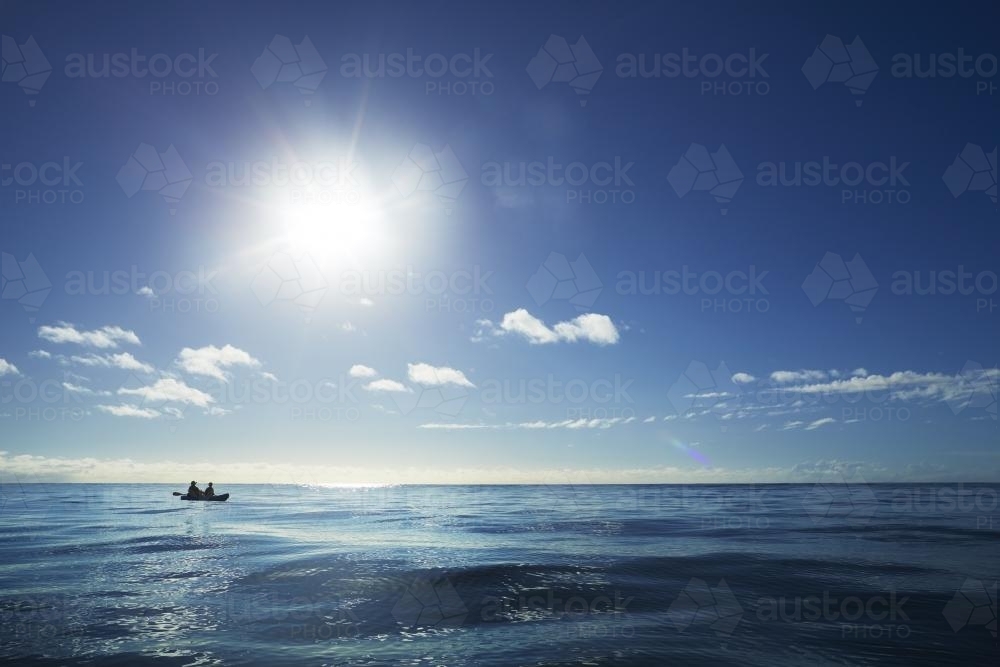 Two people paddle a kayak on a blue ocean - Australian Stock Image