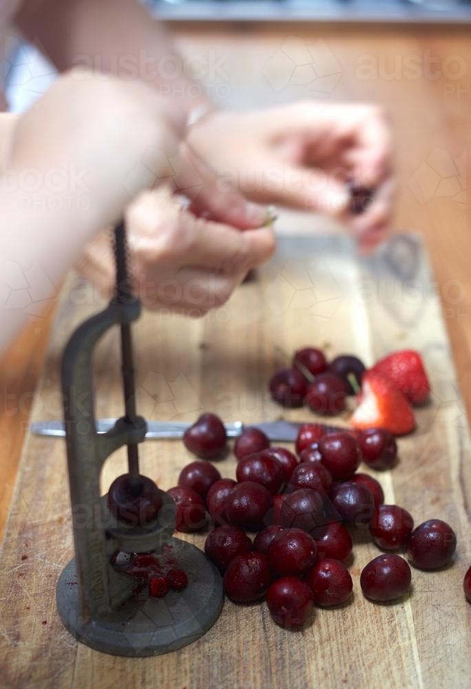 Two people pitting cherries for a cake - Australian Stock Image