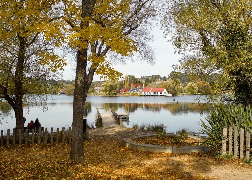 Two people sitting on the bench by the lake - Australian Stock Image