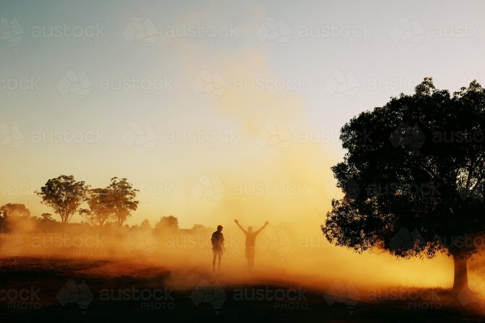 Two people walking through dust in the country. - Australian Stock Image