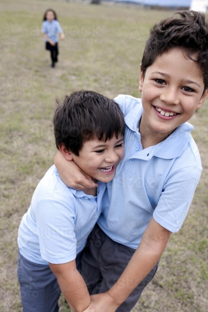 Two primary school boys in uniform playing outside - Australian Stock Image