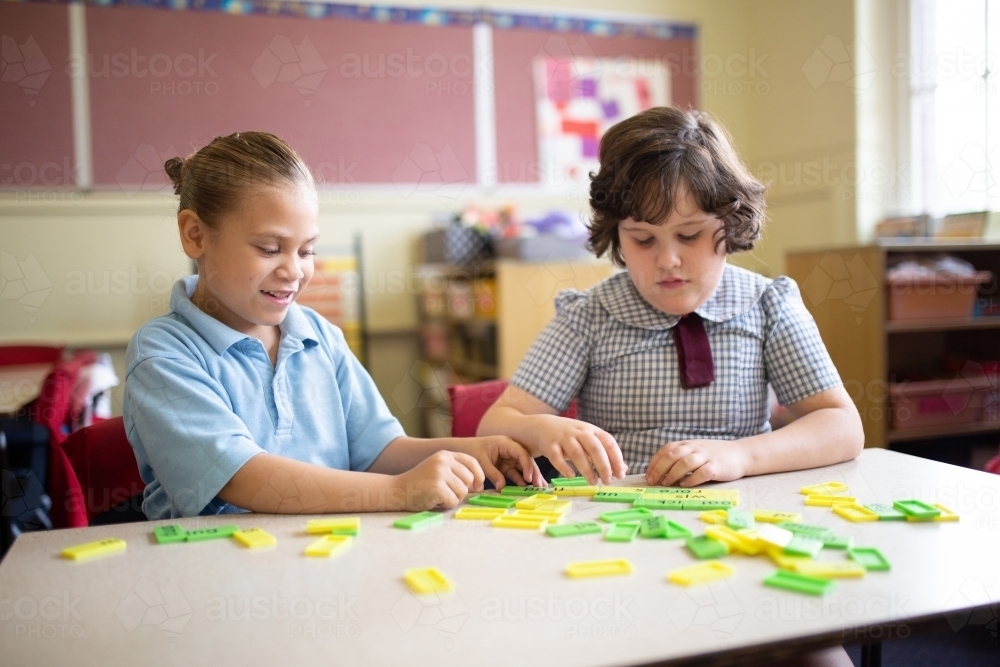 Two primary school girl students collaborating with coloured word tiles - Australian Stock Image