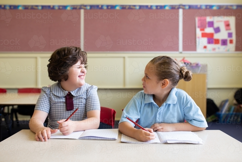 Two primary school girl students in a classroom looking at each other - Australian Stock Image