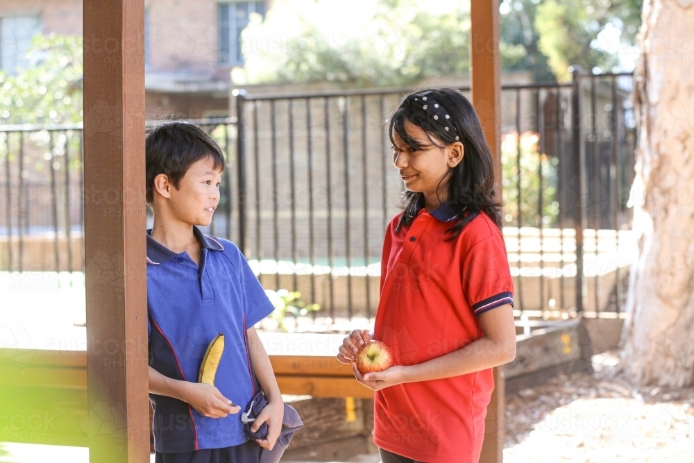 two primary school students holding healthy food for fruit break - Australian Stock Image