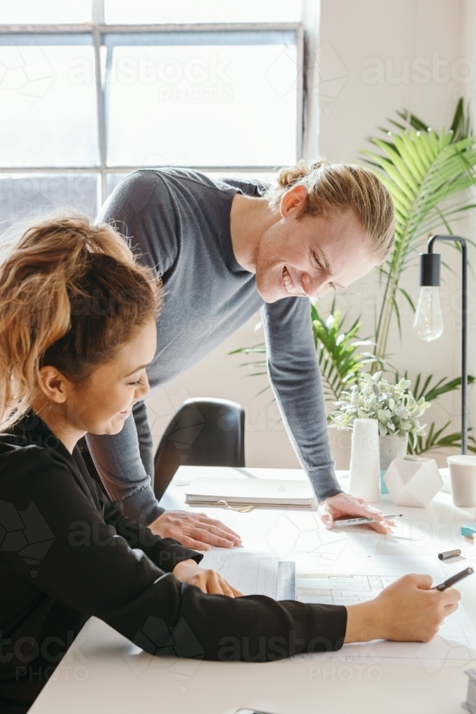 Two professionals working in a studio discussing a floor plan - Australian Stock Image