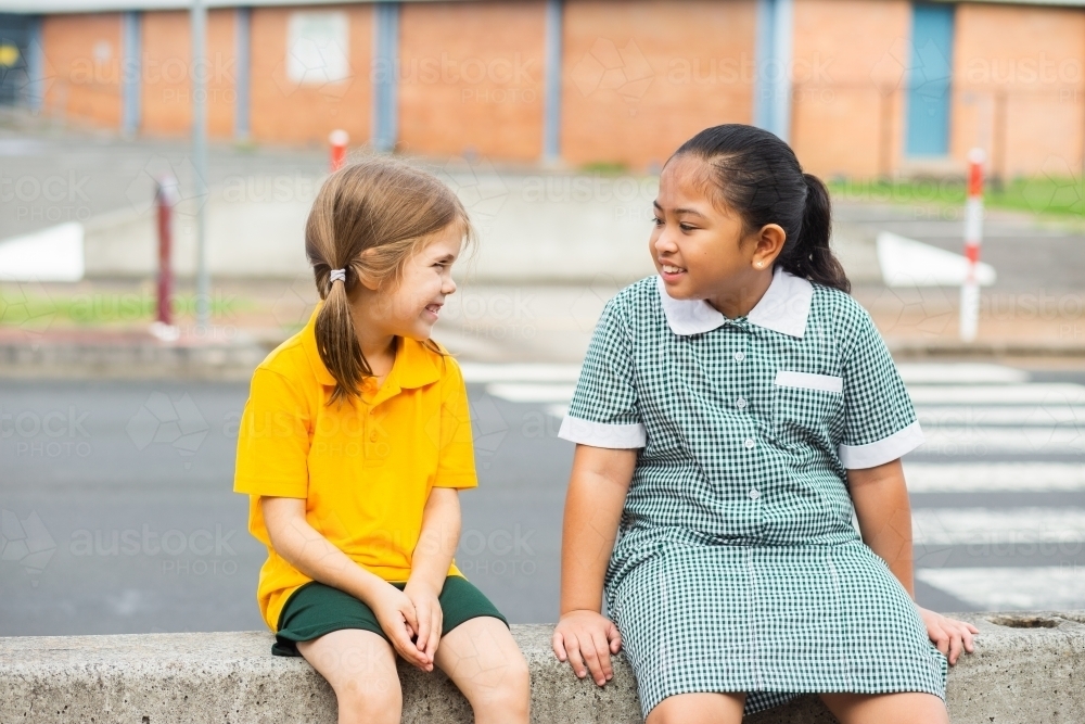 Two public school friends sitting together before school - Australian Stock Image