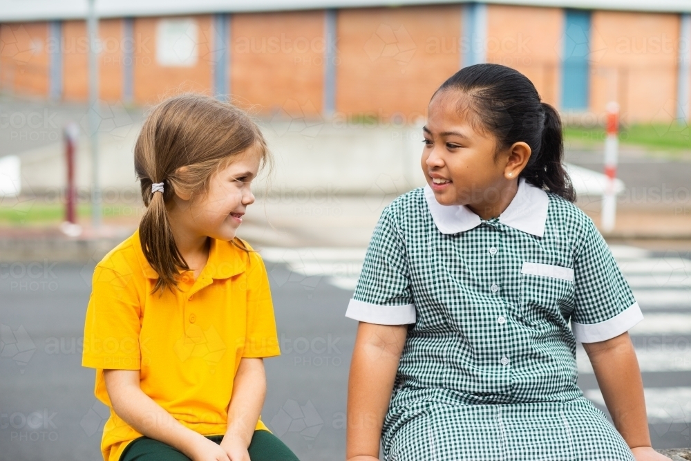 Two public school friends sitting together before school - Australian Stock Image