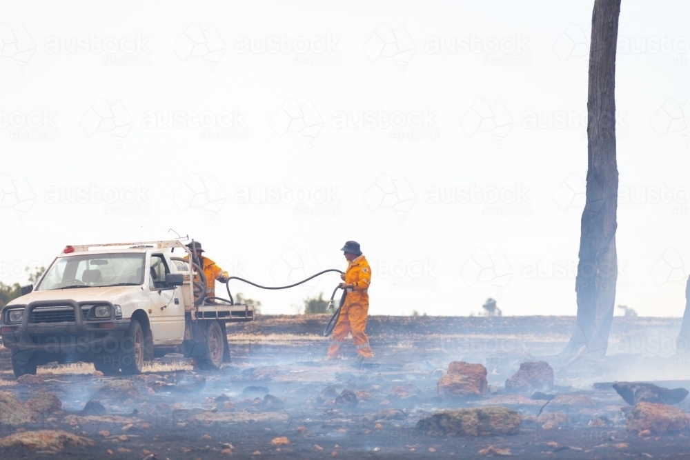 Two rural fire service volunteers in smoke packing up after fighting a fire - Australian Stock Image