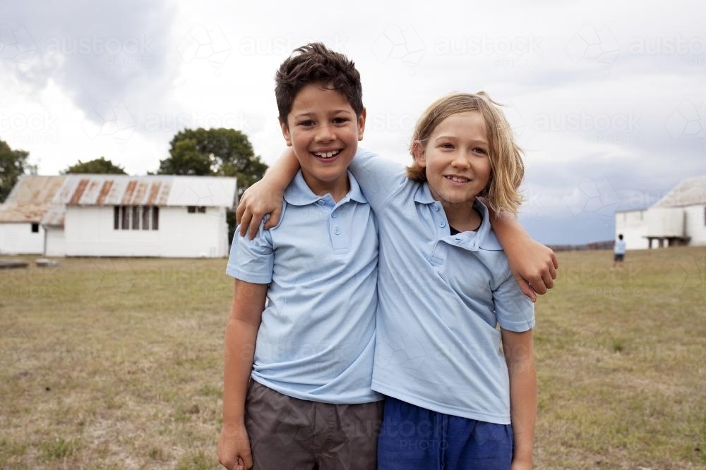 Two school friends standing together with arms around each other - Australian Stock Image