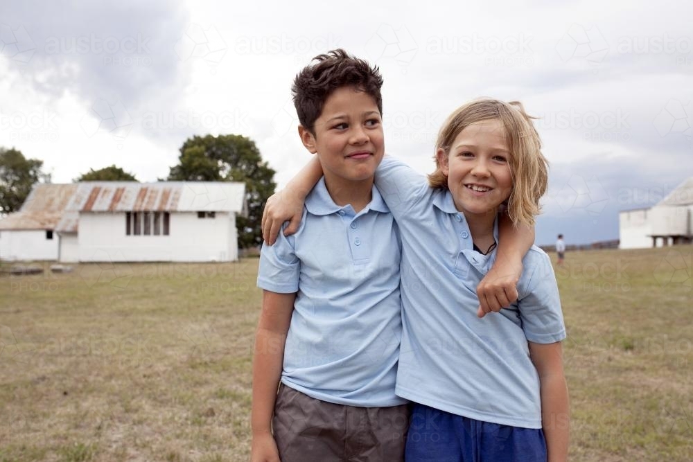 Two school friends standing together with arms around each other - Australian Stock Image