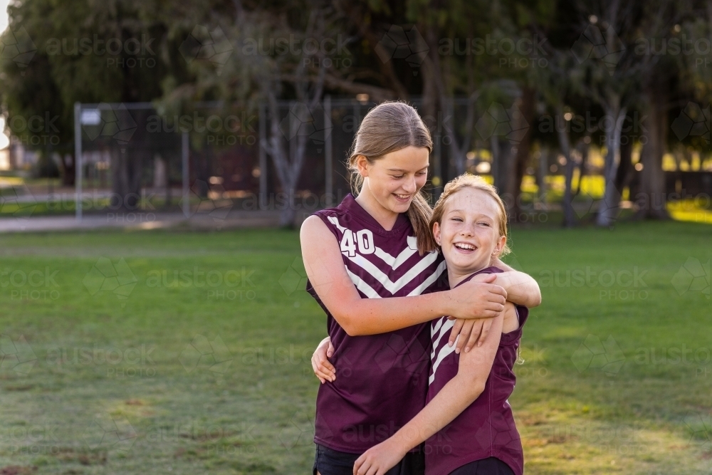 Image of two schoolgirl football players with arms around each other ...