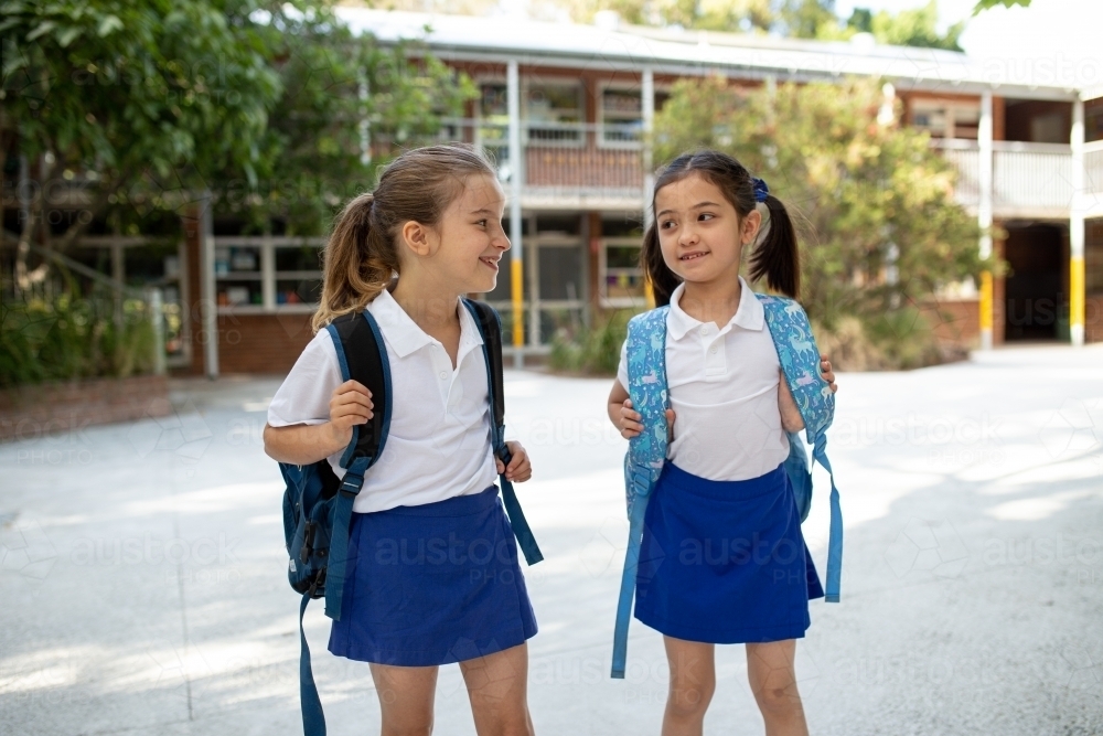 Image of Two Schoolgirls Smiling at Each Other in Playground - Austockphoto