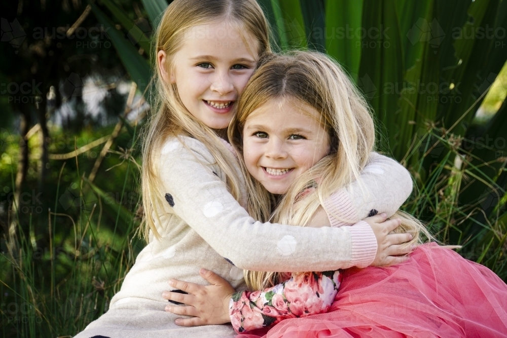 Two sisters holding each other looking at camera - Australian Stock Image