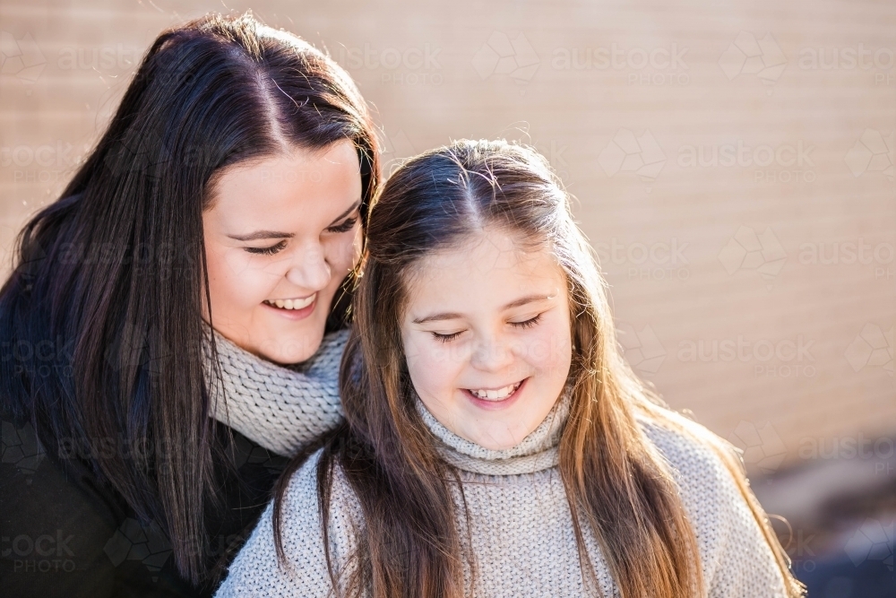 Two sisters looking down laughing together - Australian Stock Image