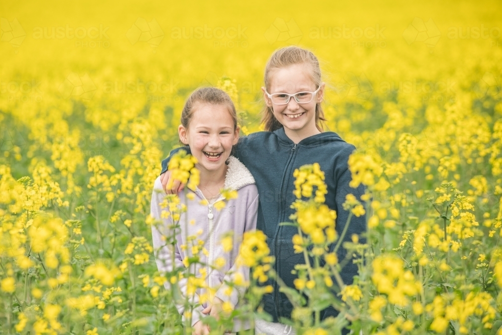 Two sisters standing in their family canola field - Australian Stock Image
