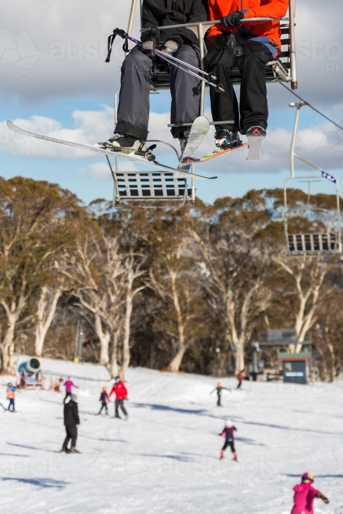 Two skiers on a chairlift with skiers in the background - Australian Stock Image