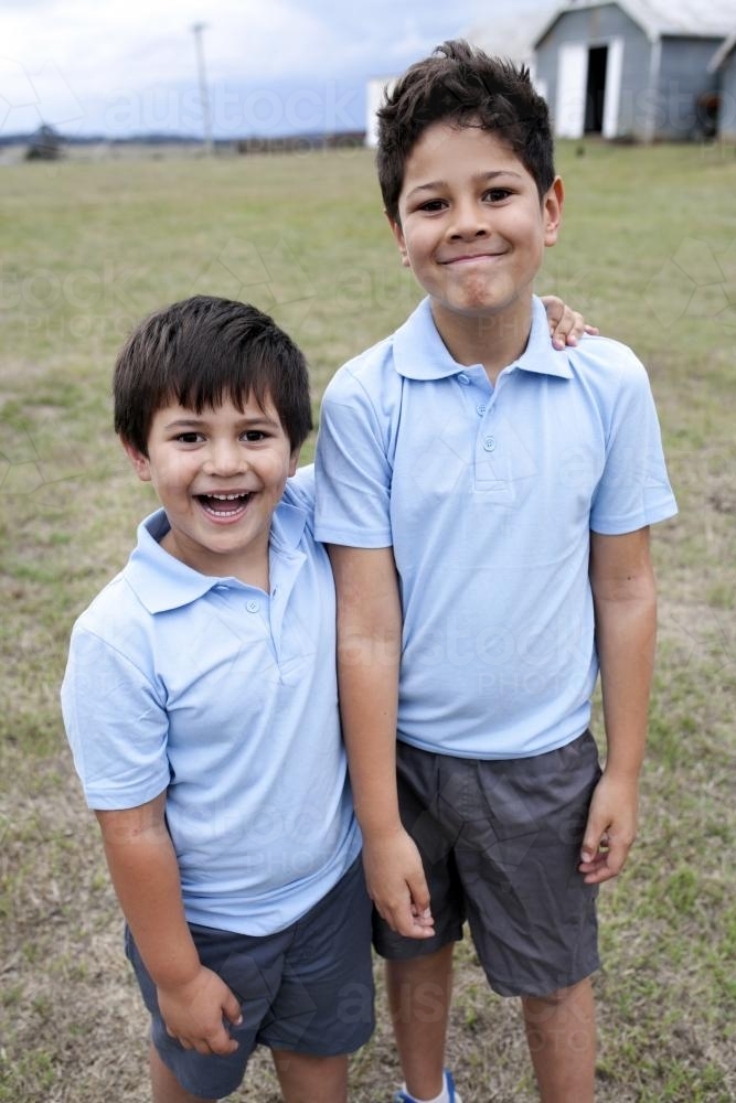Two smiling boys standing outside wearing school uniform - Australian Stock Image
