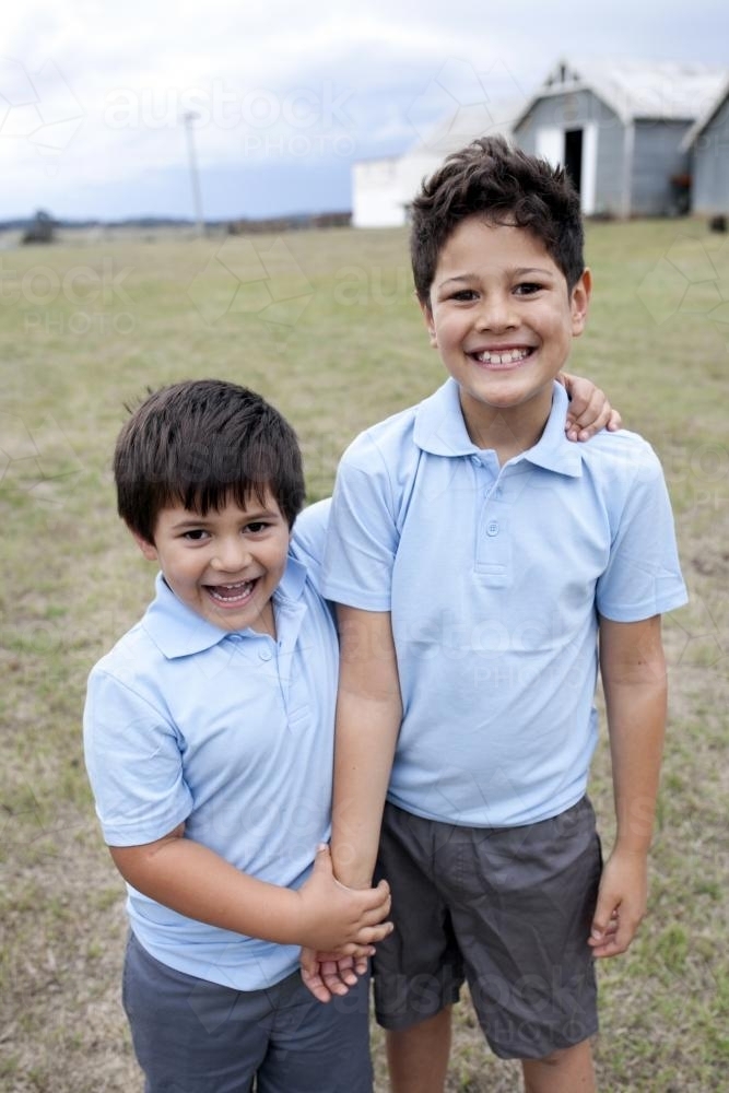 Two smiling boys standing outside wearing school uniform - Australian Stock Image