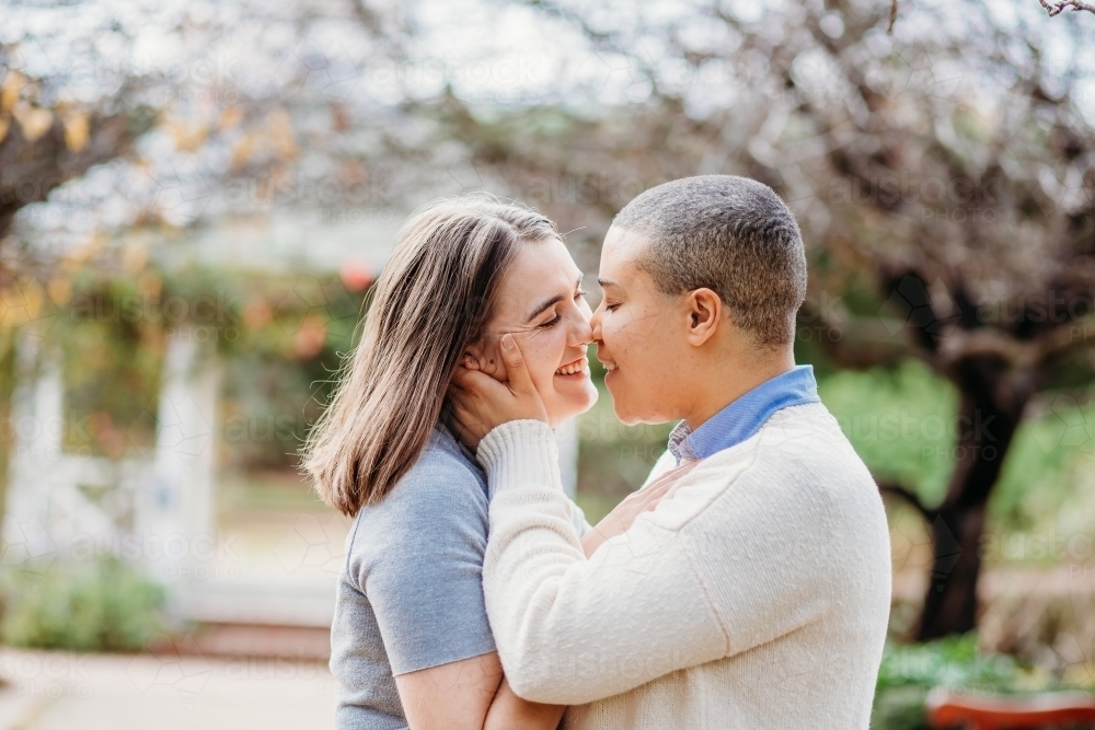 Smiling lgbtqi couple being intimate holding one another - Australian Stock Image