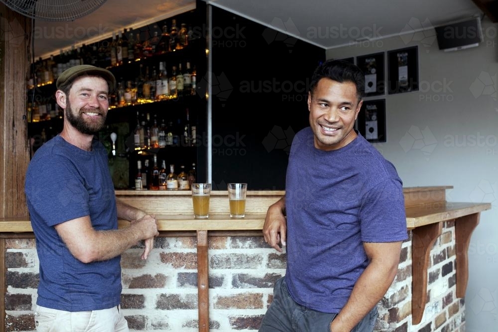 Two smiling men enjoying drink at local craft beer bar - Australian Stock Image