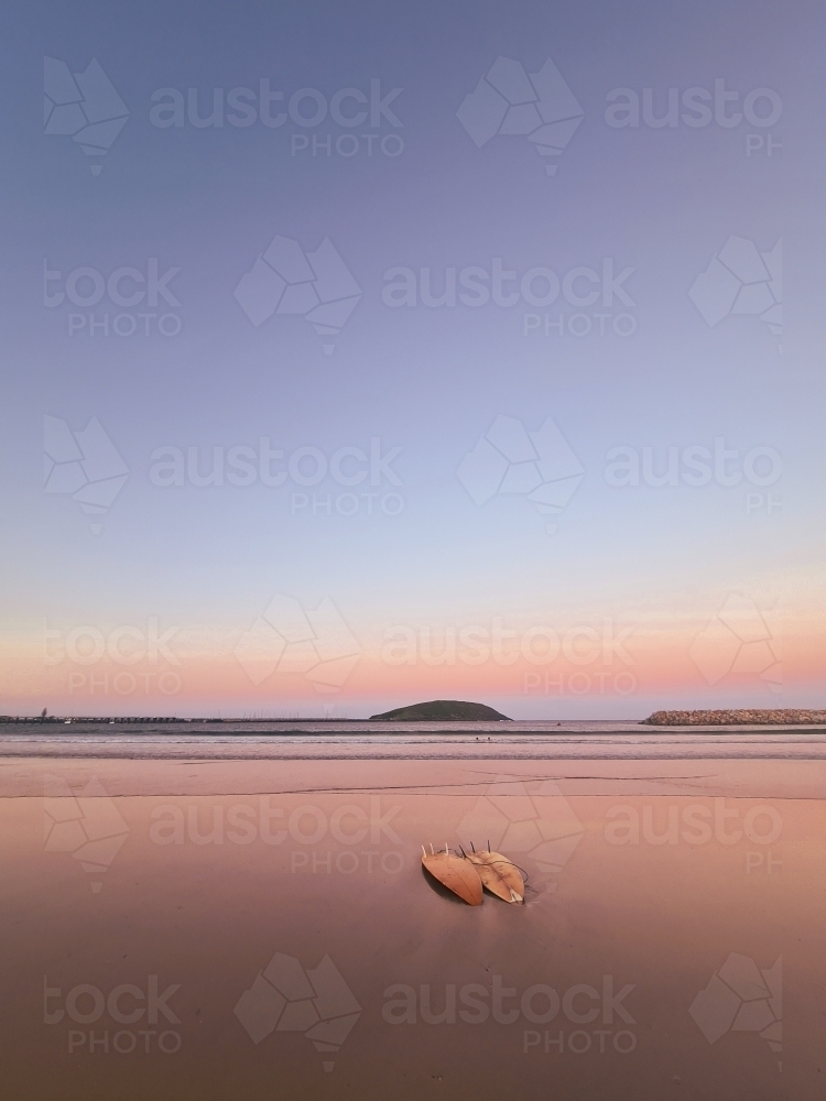 Two surfboards on the sand as the sun sets near the beach - Australian Stock Image