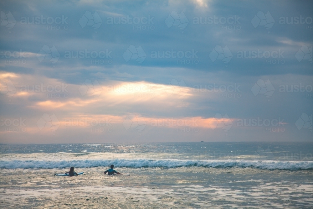 Two surfers making their way out to the breakers in early morning - Australian Stock Image