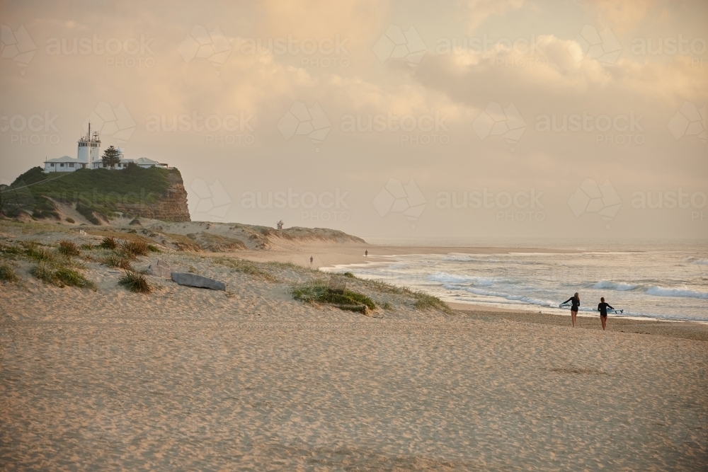 Two surfers walking to ocean at sunset - Australian Stock Image