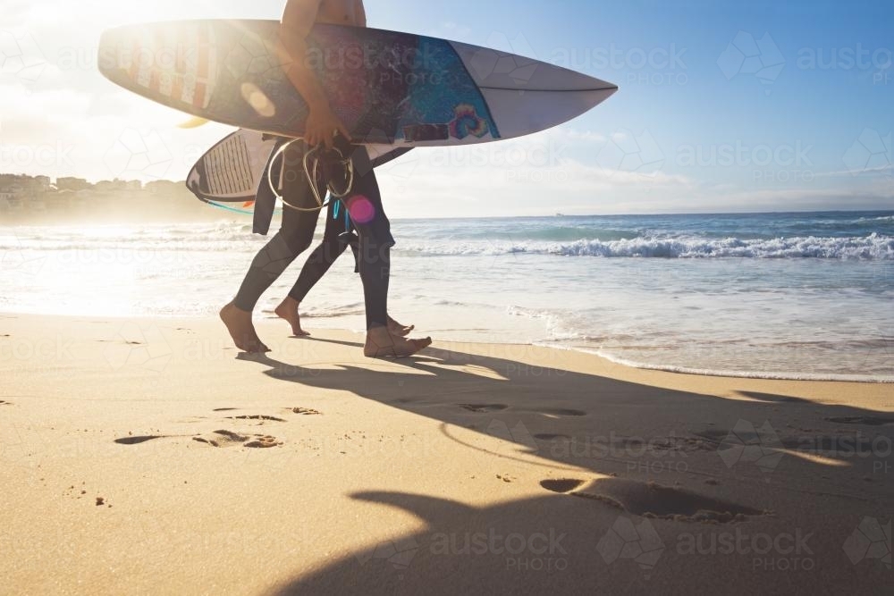 Two surfers walking with surfboards on Bondi Beach - Australian Stock Image