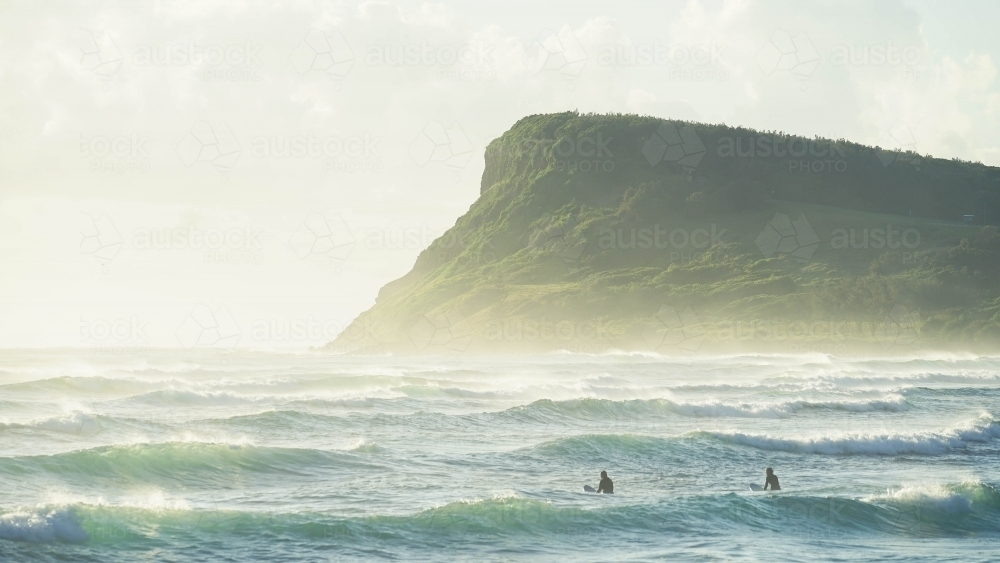 Two surfers with Lennox Headland in background - Australian Stock Image