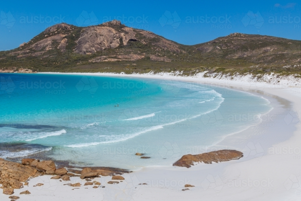 Two swimmers enjoying the clear blue waters of a deserted beach - Australian Stock Image