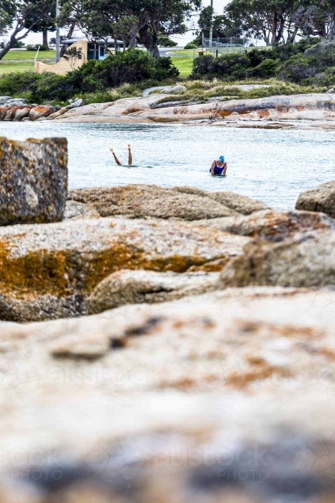 two swimmers in the water, one doing an underwater handstand - Australian Stock Image
